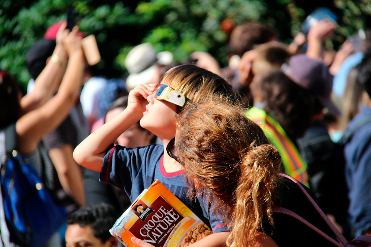 Eclipse solaire, enfant avec lunettes de protection au soleil au milieu de la foule